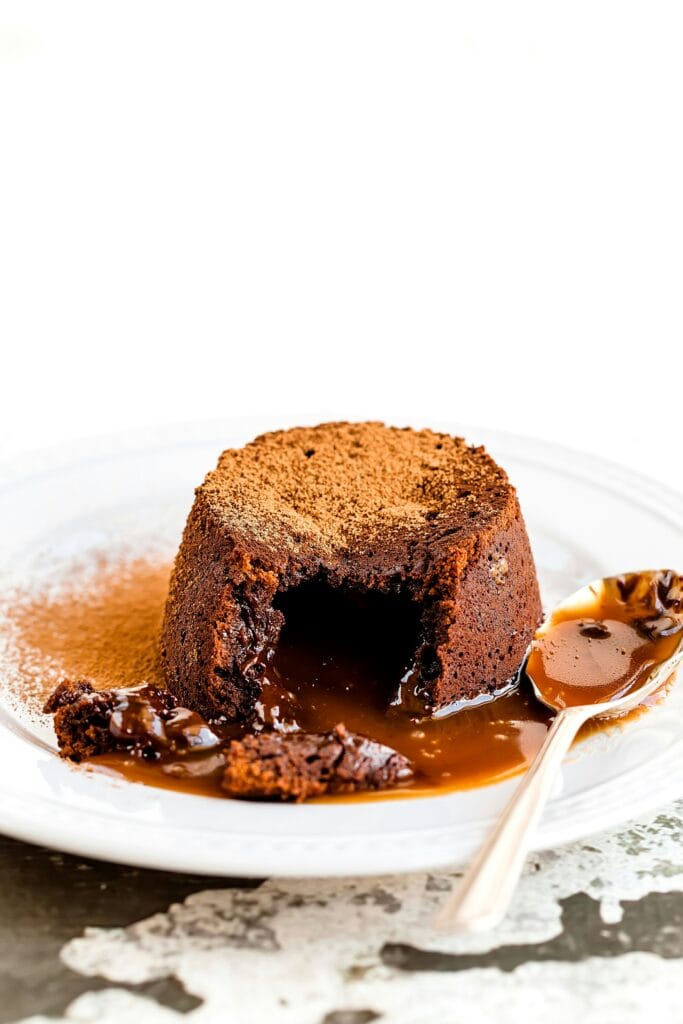 A warm serving of toffee pudding drizzled with caramel sauce and garnished with whipped cream.