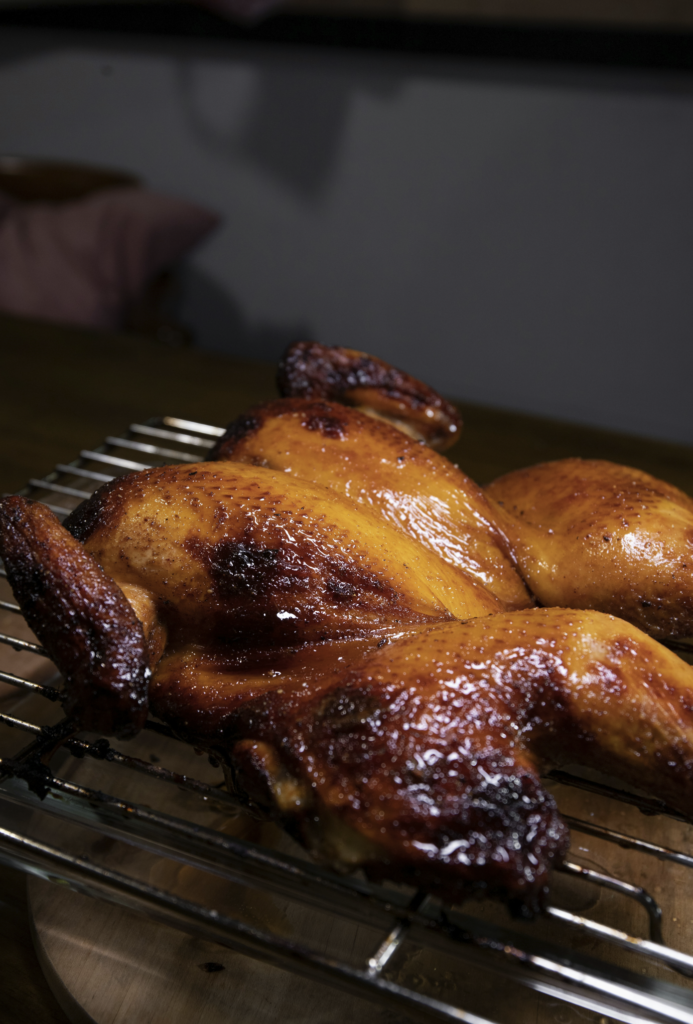 A golden-brown rotisserie chicken with a side of fresh herbs, showcasing a perfectly cooked meal for various recipes.