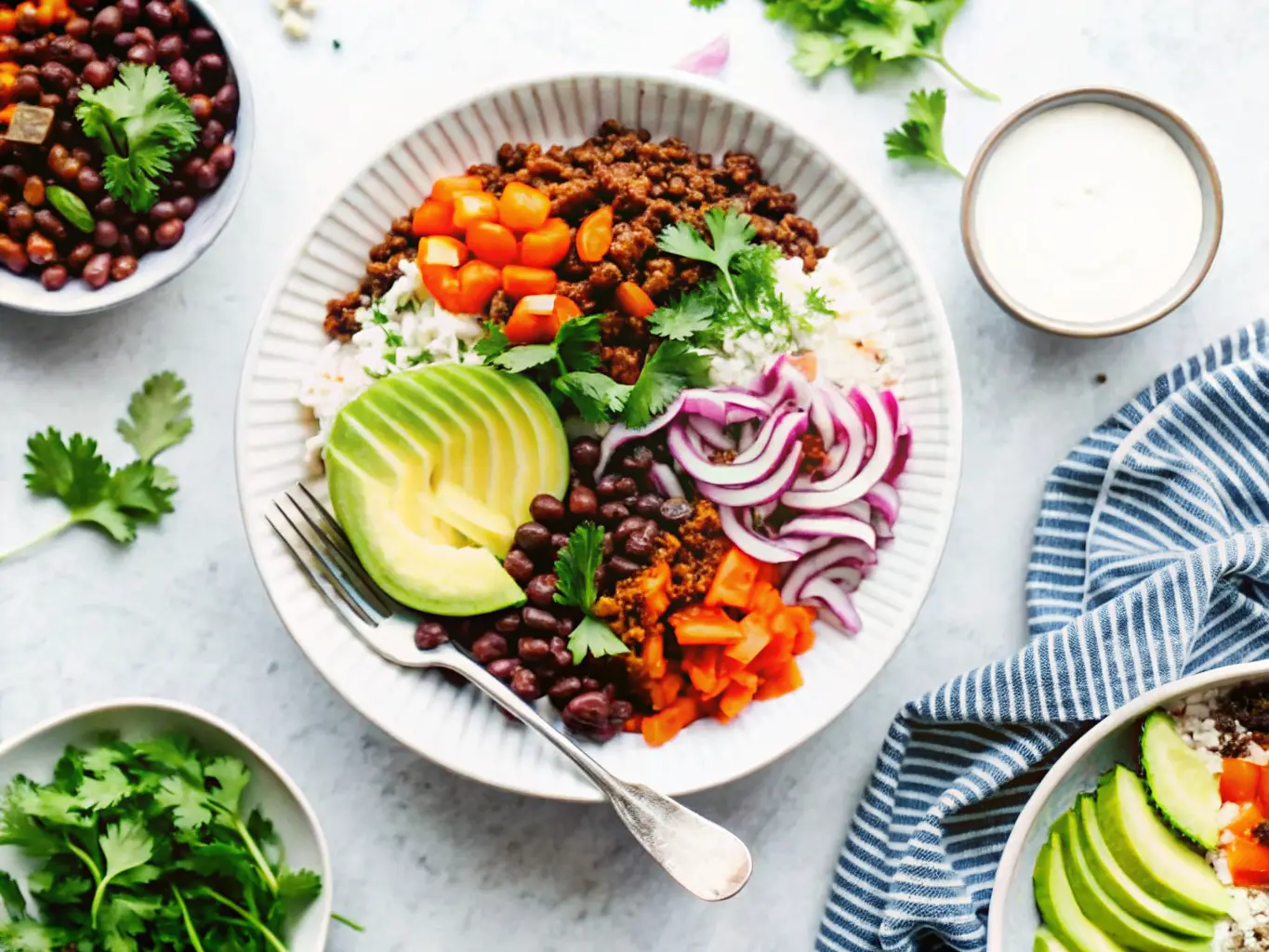 A hero shot of a vibrant Beef Burrito Bowl in a textured off-white ceramic bowl, brimming with fluffy white cilantro lime rice, richly seasoned dark brown ground beef, dark black beans, orange-brown roasted sweet potato cubes, fanned sliced bright green avocado, and light purple pickled red onion strips. Garnish with fresh green cilantro leaves and a small yellow-green lime wedge. The bowl is centered on a light grey marble countertop, with soft natural morning light from an east window casting subtle shadows. In the background, hints of a wooden cutting board, scattered fresh cilantro sprigs, and a small dark ceramic bowl containing a creamy pale green sauce are visible. Warm tones and a clean, tidy presentation. No hands or people.