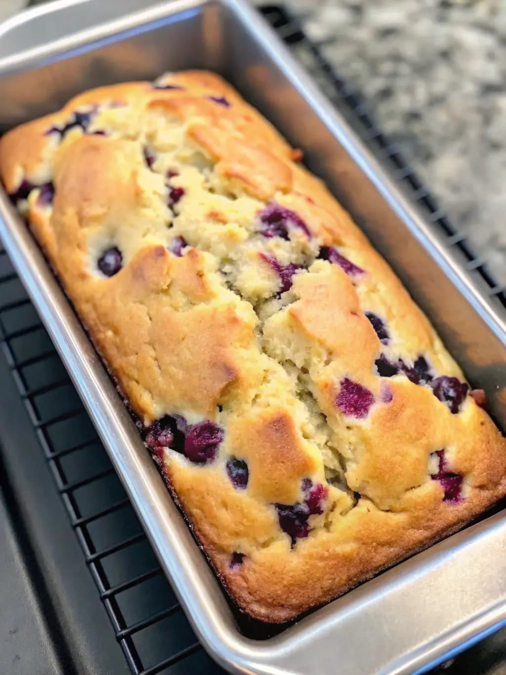 An overhead shot of fresh blueberries, softened cream cheese, flour, sugar, and other baking ingredients for Blueberry Cream Cheese Loaf neatly arranged in minimalist white ceramic bowls on a white marble countertop. Fresh herbs (e.g., mint or basil sprig) are visible in the background. Natural morning light, warm tones, clean and tidy. NO HANDS OR PEOPLE.