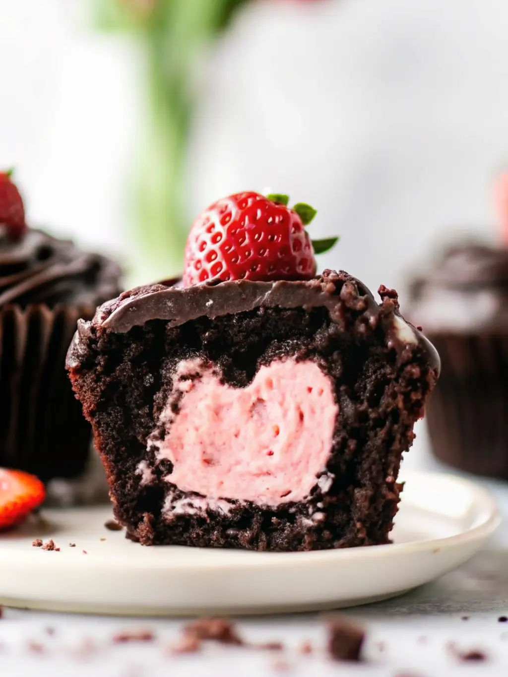 A close-up shot of partially baked chocolate cupcakes in a muffin tin, with the unbaked strawberry heart filling peeking slightly from the chocolate batter in one of the cupcake liners. The scene is on a marble countertop, illuminated by soft natural morning light. Warm tones and soft shadows. No hands or people. (3:4 ratio)
