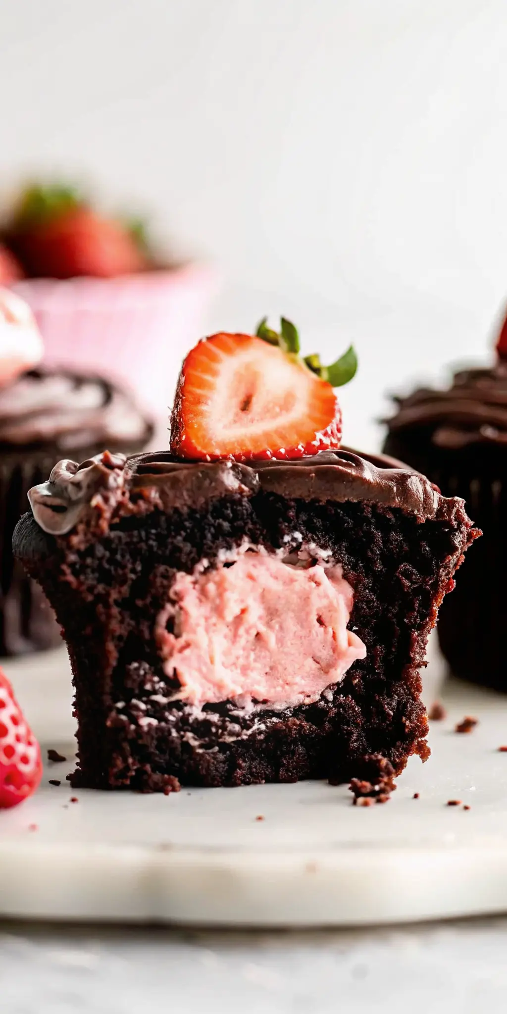 A single, perfectly baked Chocolate Covered Strawberry Cupcake, sliced cleanly in half, showcasing the vibrant pink strawberry cream heart perfectly nestled within the dark chocolate cake. It's elegantly presented on a minimalist white plate on a marble countertop, garnished with a fresh strawberry on top and glossy chocolate ganache. Natural morning light, soft shadows, and warm tones create an inviting atmosphere. No hands or people. (3:4 ratio)