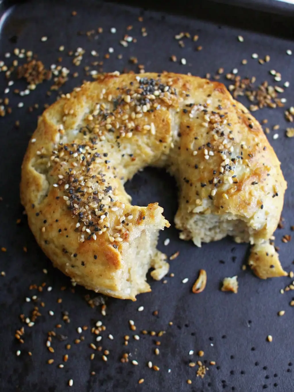 Close-up of a perfectly formed, unbaked Greek Yogurt Bagel dough ring on a wooden cutting board, lightly dusted with flour, showing its smooth texture, ready for toppings. Natural morning light from an east window, soft shadows, warm tones. NO HANDS OR PEOPLE.