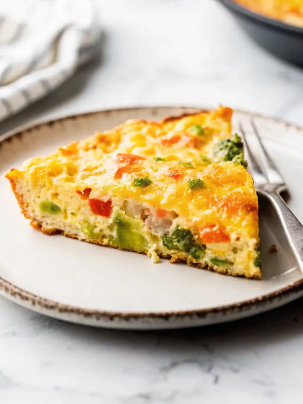 A black cast iron skillet on a marble countertop, filled with sautéed, tender-crisp broccoli florets, red and green bell peppers, and yellow onion. A bowl of whisked golden egg mixture, prepared with a splash of milk and a hint of baking powder, is positioned next to the skillet, just before pouring. The scene is bathed in warm natural morning light, showing the cooking process in a clean and appealing way. (3:4 ratio)