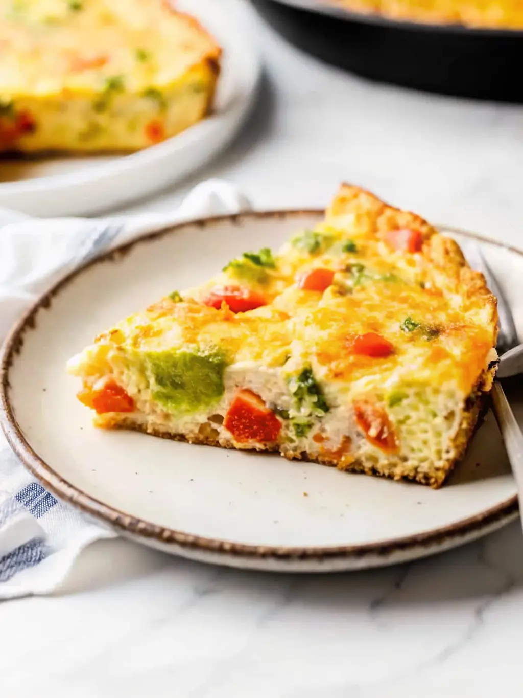A close-up shot of a sliced golden-yellow frittata in a black cast iron skillet, revealing its fluffy, airy interior with visible broccoli and colorful bell pepper pieces. A single slice is partially pulled away, showing the texture. The skillet rests on a marble countertop, with a minimalist white plate and a fork positioned to the side, ready for serving. Fresh parsley sprigs are scattered lightly on top as a garnish. Soft morning light and warm tones highlight the inviting texture. (3:4 ratio)