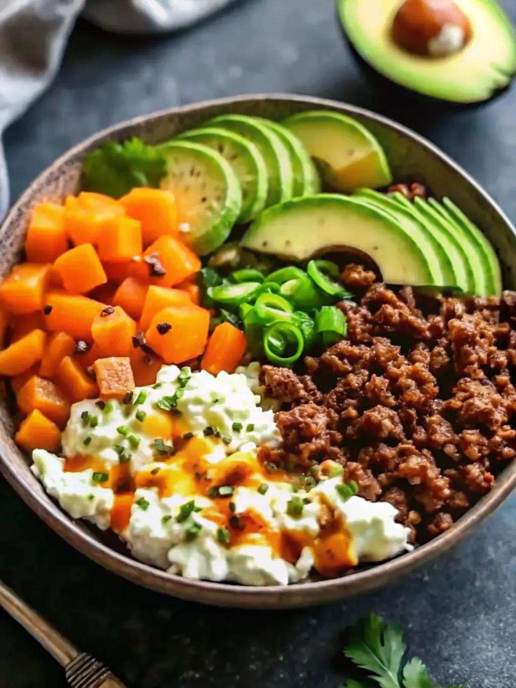 Ingredients for Ground Beef Hot Honey Bowl neatly arranged on a wooden cutting board next to a marble countertop. Visible items include a ceramic bowl of raw ground beef, diced butternut squash, a bottle of hot honey, a whole avocado, a small bowl of ricotta, and fresh cilantro and green onions. Natural morning light, warm tones, clean and tidy presentation. 3:4 ratio. NO HANDS OR PEOPLE.