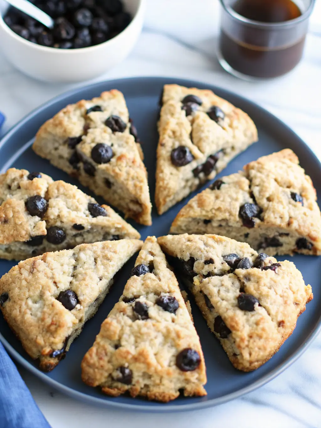 Ingredients for Sourdough Chocolate Chip Scones laid out on a clean marble countertop with wood accents. Visible elements include a bowl of all-purpose flour, cold grated butter, a jar of bubbly sourdough discard, a measuring cup of heavy cream, and a small bowl of dark chocolate chunks. Fresh herbs are subtly in the background. Soft morning light creates a warm, inviting atmosphere. (3:4 ratio)
