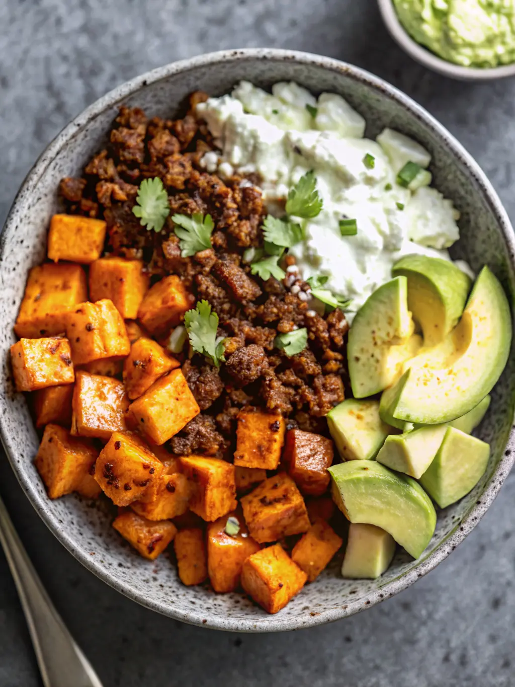 A beautiful close-up of vibrant, freshly chopped sweet potato cubes ready for roasting on a wooden cutting board, with a small bowl of taco seasoning and a sprig of fresh cilantro in the background on a marble countertop, bathed in natural morning light. The scene emphasizes fresh ingredients and preparation, no hands visible.
